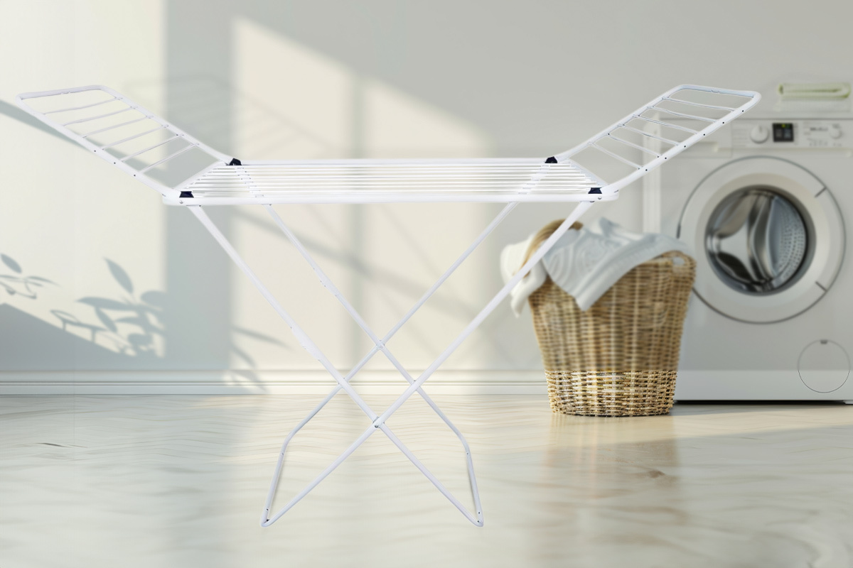 Stendino pieghevole bianco posizionato in una lavanderia luminosa. Questo stendino salvaspazio è perfetto per interni o come stendibiancheria da balcone. La struttura leggera e richiudibile lo rende ideale anche per piccoli spazi e per chi cerca uno degli stendini da balcone più pratici. La sua versatilità lo colloca tra i migliori stendibiancheria per l'uso quotidiano, sia in casa che all'aperto.