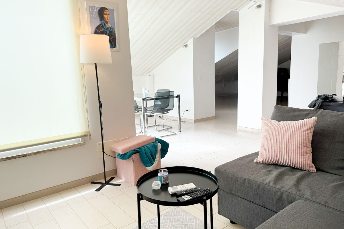 Arredamento salotto luminoso con pareti chiare, specchi e tende leggere