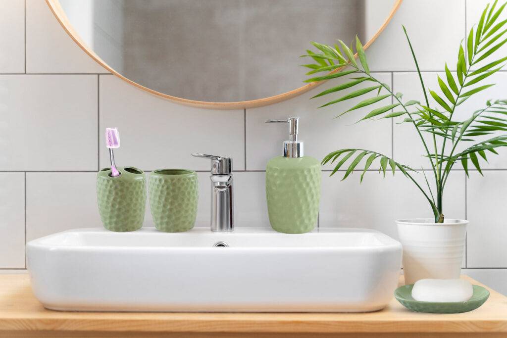 Accessori bagno coordinati: dispenser, porta spazzolino e bicchiere in ceramica su lavabo moderno