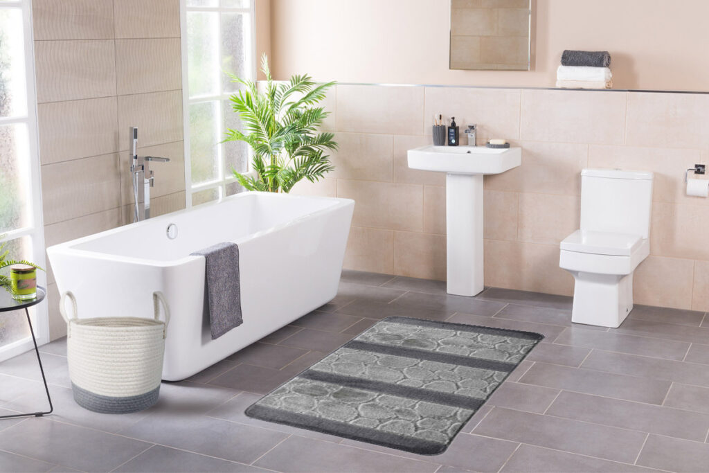 Bagno rinnovato con accessori beige e verdi, tappeto in coordinato e pianta decorativa