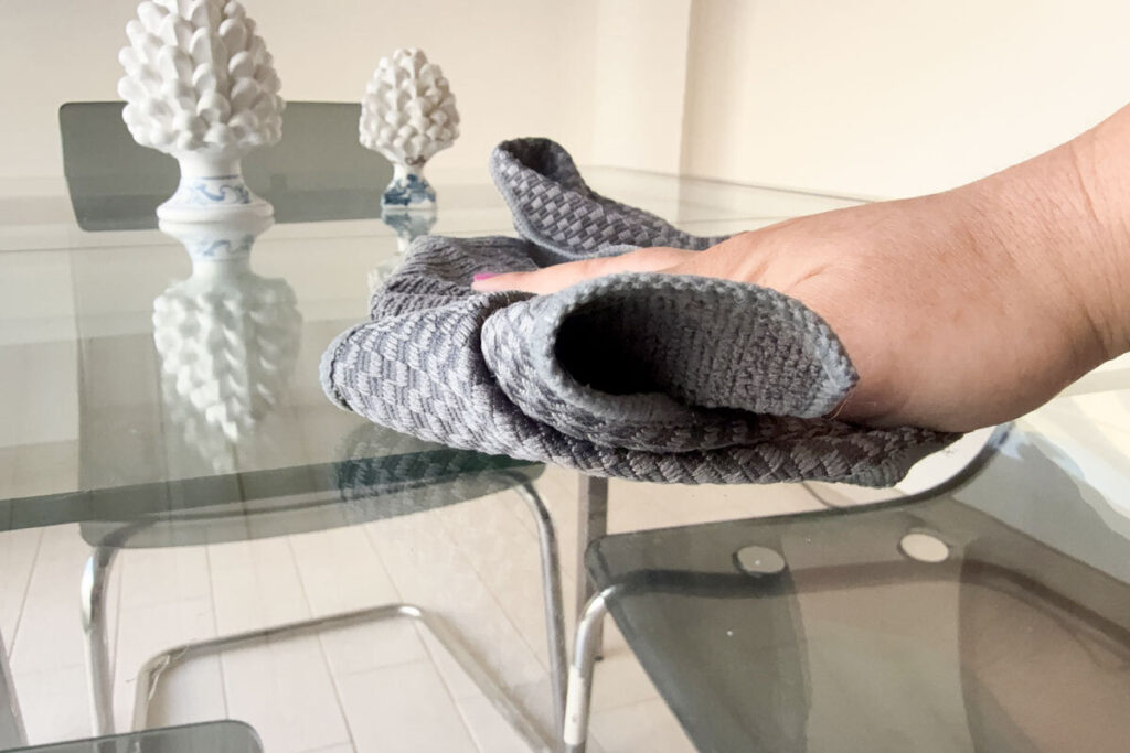 Donna che spolvera mensole con panno in microfibra
