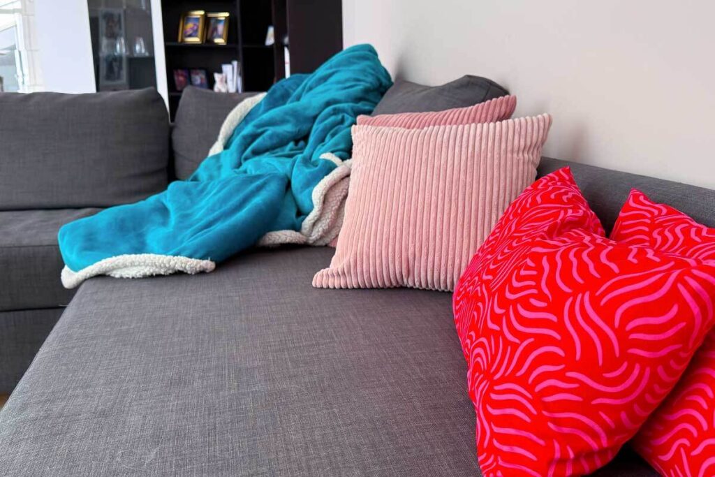 Plaid morbido e cuscini caldi su divano per rendere la casa accogliente a fine inverno